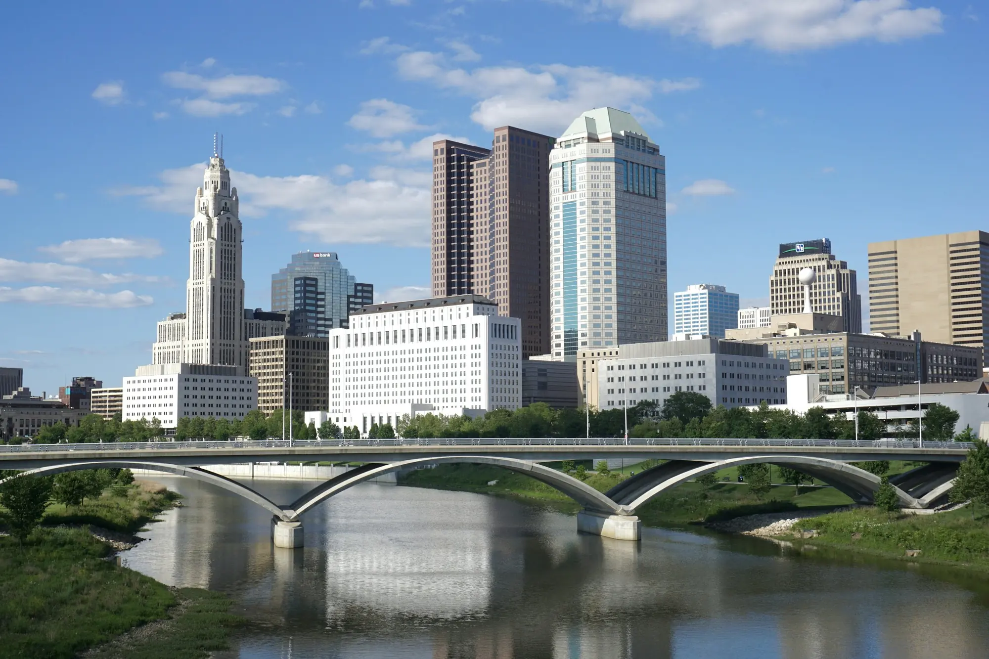 Downtown Columbus skyline across the river, with an arched bridge