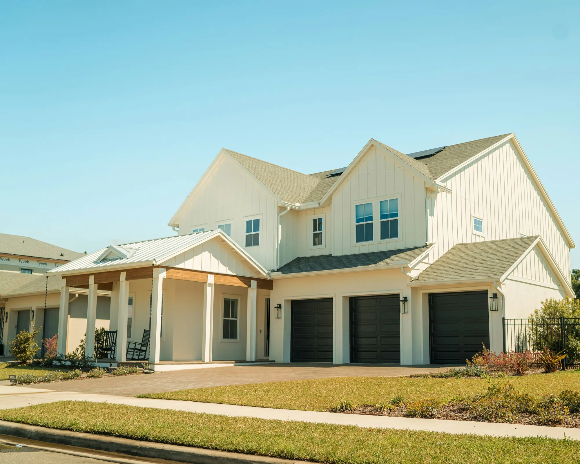 White two-story farmhouse with a three-car garage and a wraparound porch