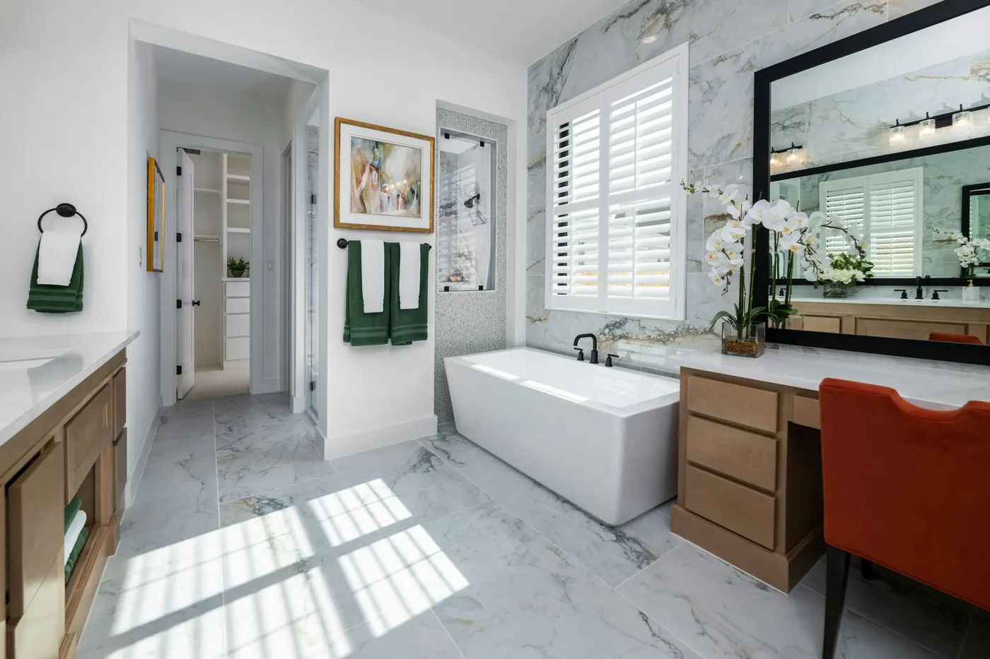 Primary bath with a freestanding tub, marble tile and a makeup vanity