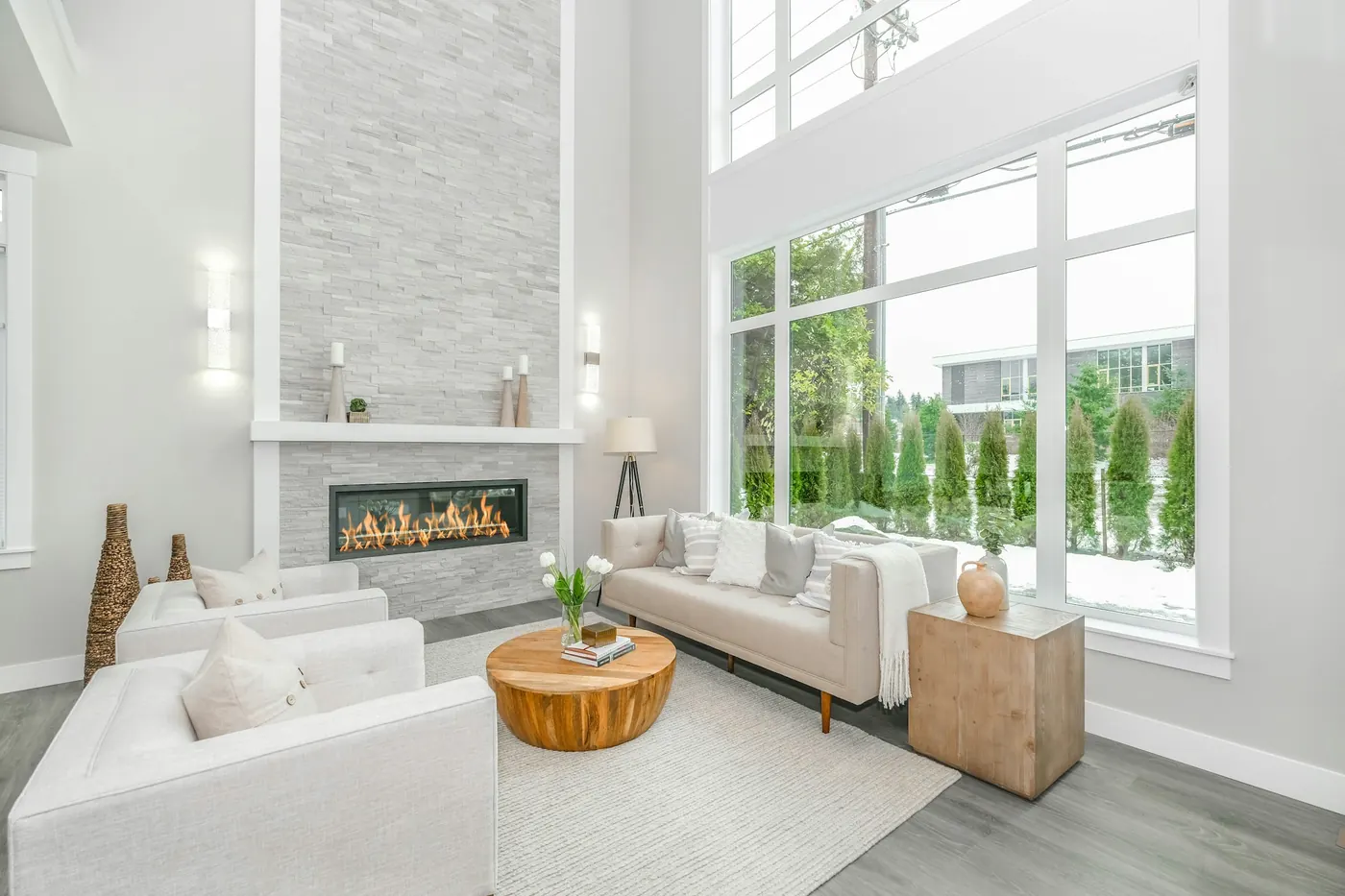 Great room with a stone fireplace wall and tall windows
