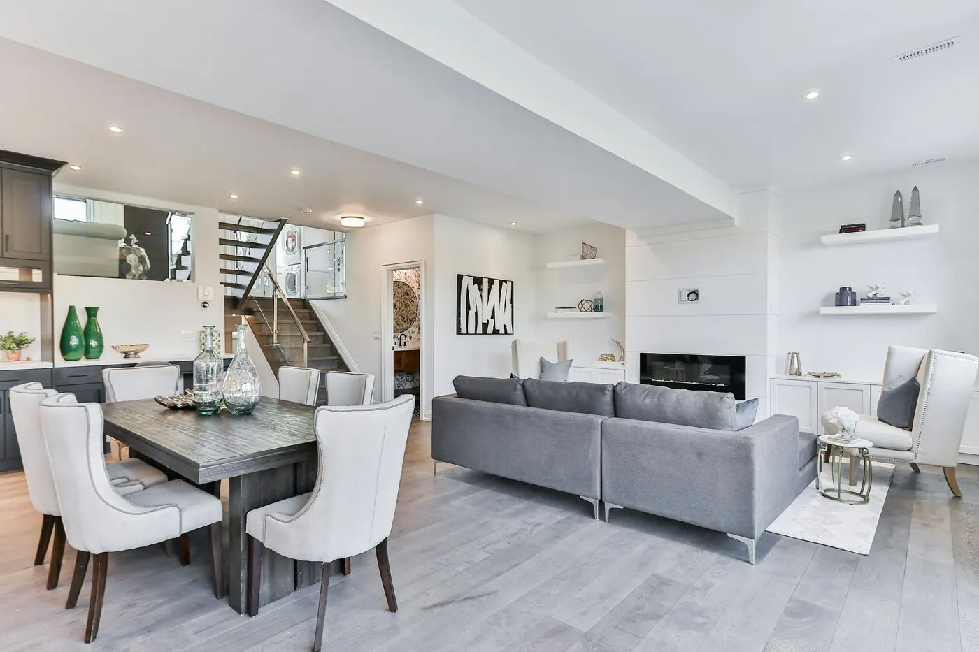 Open dining and living room with a linear fireplace and a staircase