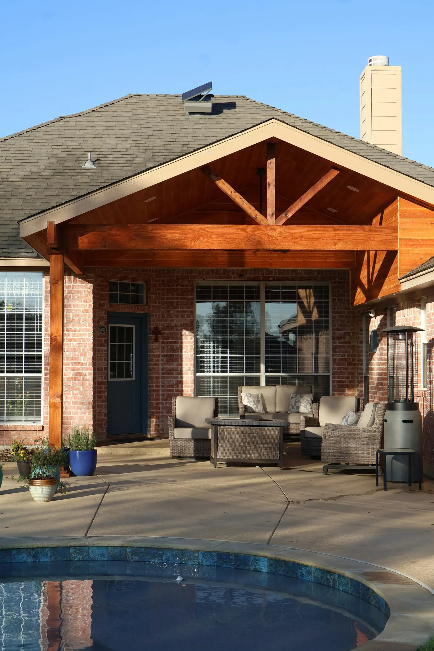 Covered back patio with a timber-framed roof and outdoor seating